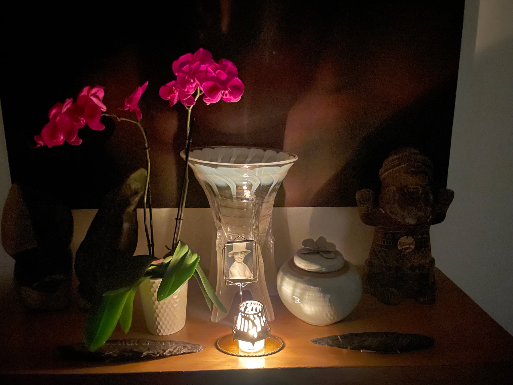 a yahzeit table with a candle, orchid, and artwork