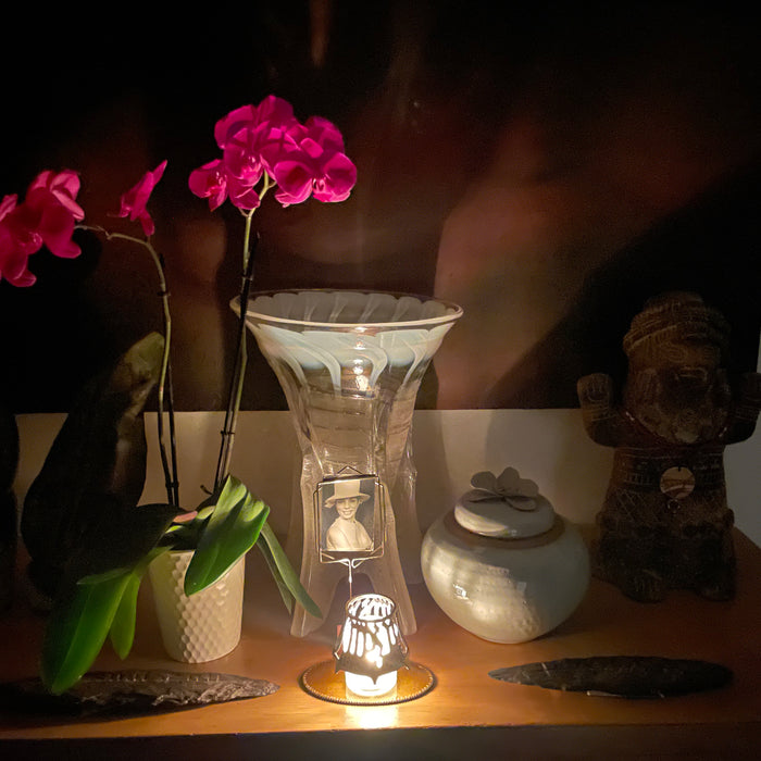 a yahzeit table with a candle, orchid, and artwork